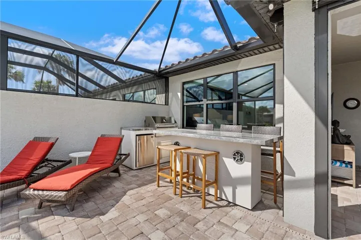 View of patio / terrace with a grill, exterior bar, exterior kitchen, and glass enclosure