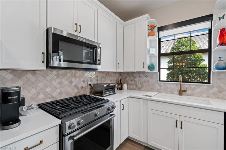 Kitchen featuring a healthy amount of sunlight, stainless steel appliances, sink, and white cabinets