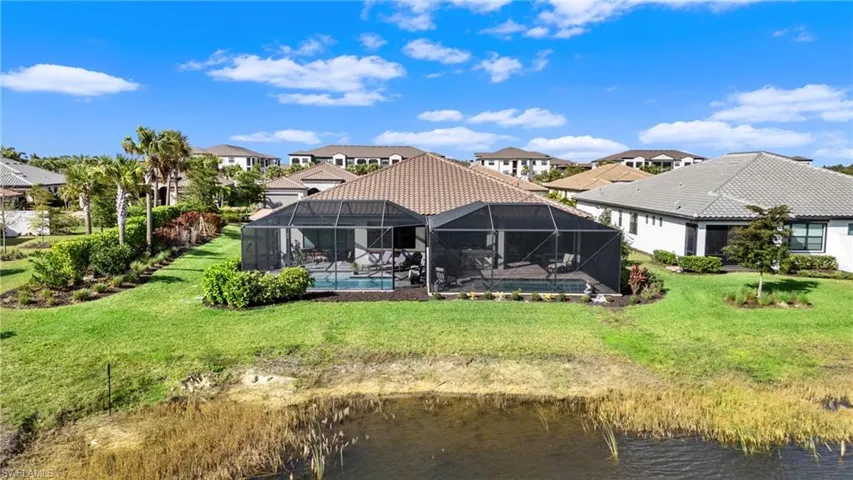 Rear view of property featuring a water view, glass enclosure, and a lawn