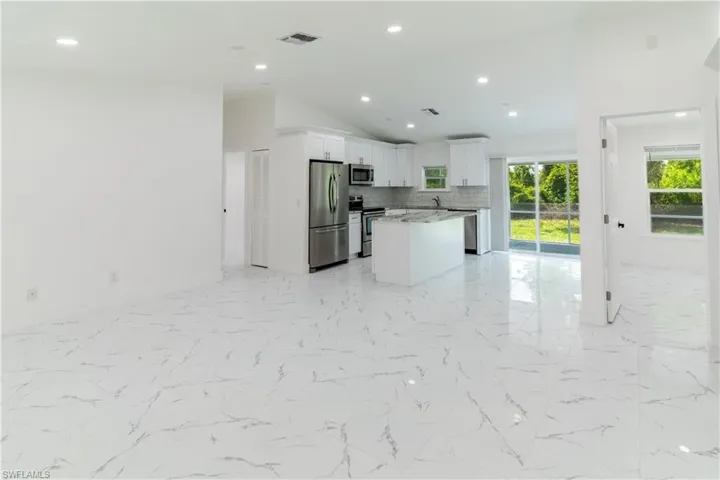 Kitchen with open floor plan, a center island, decorative backsplash, white cabinetry, and vaulted ceiling