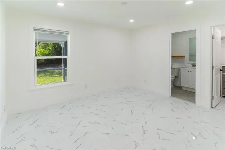 Unfurnished bedroom featuring recessed lighting, light marble finish flooring, and ensuite bathroom