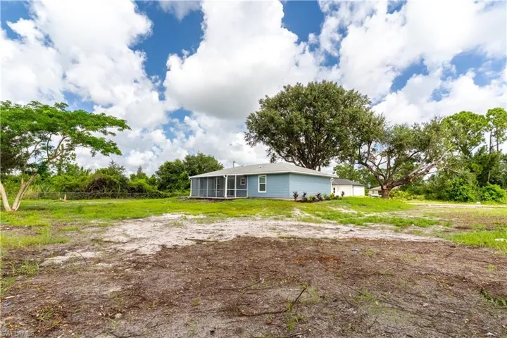 Back of property with a sunroom, a lawn, and view of scattered trees