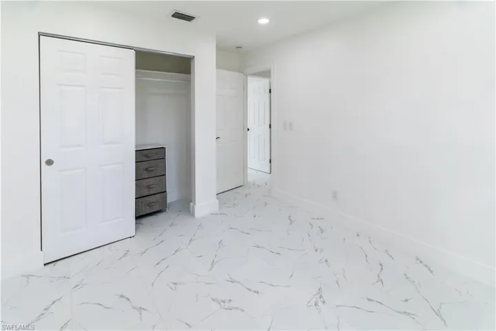 Unfurnished bedroom featuring light marble finish flooring, a closet, and recessed lighting