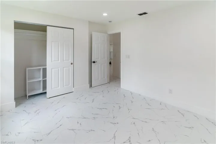 Unfurnished bedroom featuring light marble finish floors, a closet, and recessed lighting
