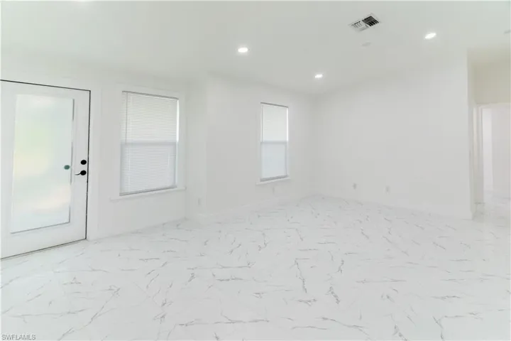 Spare room featuring healthy amount of natural light, recessed lighting, and light marble finish floors