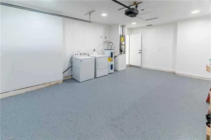 Garage featuring electric water heater, washing machine and dryer, a garage door opener, and recessed lighting