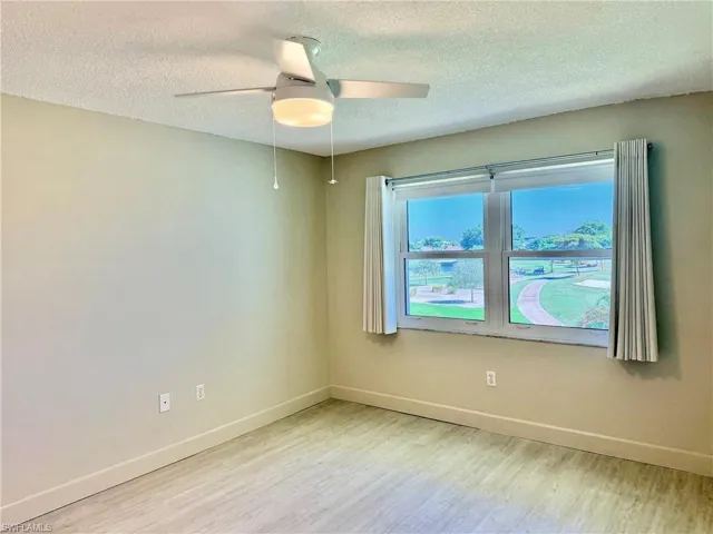 Interior space featuring LVP flooring, a ceiling-mounted light fixture with fan, and large windows with horizontal blinds