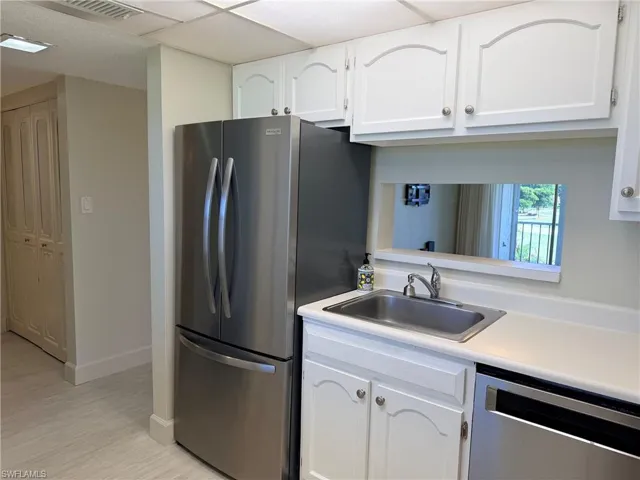 Kitchen featuring white cabinetry, stainless steel French-door refrigerator, stainless steel dishwasher, stainless steel sink, and light-toned LVP flooring