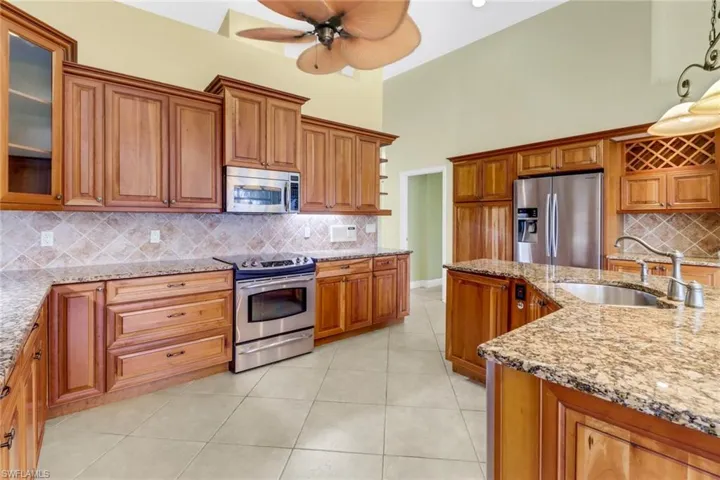 Kitchen featuring light stone countertops, sink, decorative backsplash, and appliances with stainless steel finishes