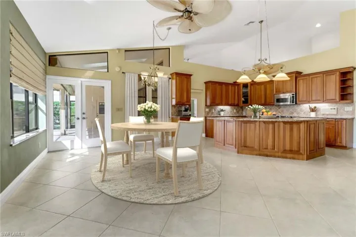 Tiled dining area with high vaulted ceiling, french doors, and ceiling fan