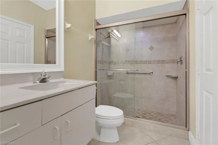 Bathroom with tile patterned flooring, vanity, toilet, and a shower with door