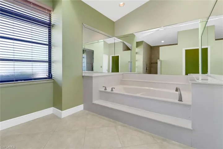 Bathroom with tile patterned flooring, lofted ceiling, and plus walk in shower