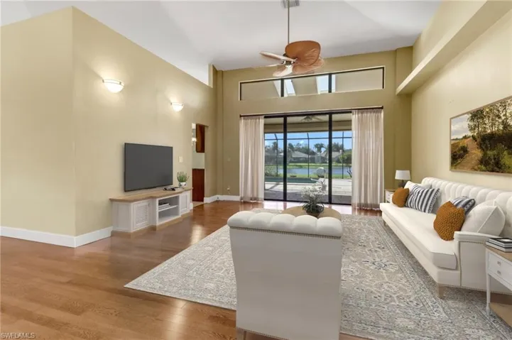 Living room with hardwood / wood-style floors, ceiling fan, and a high ceiling