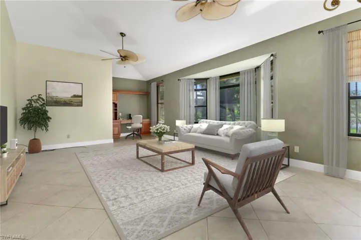 Living room with ceiling fan, vaulted ceiling, and light tile patterned floors