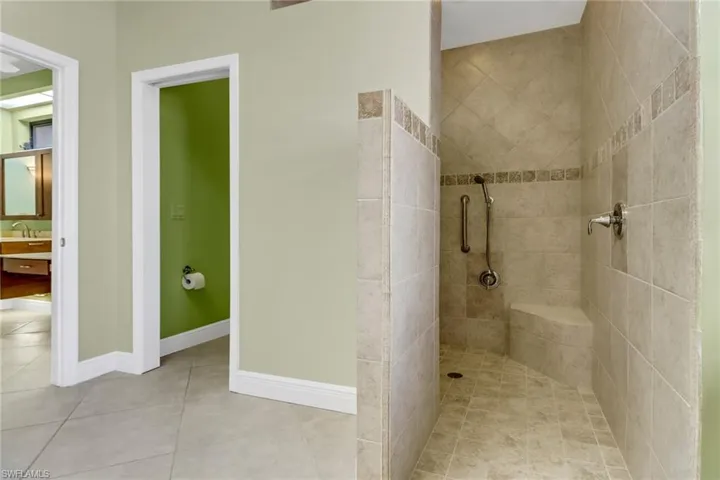 Bathroom with vanity, tile patterned floors, and a tile shower