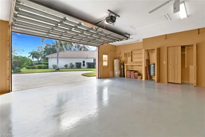 Garage featuring water heater, a garage door opener, and ceiling fan