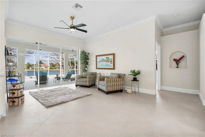 Living room featuring designer 45 degree tile floors, crown molding, ceiling fan and water views.