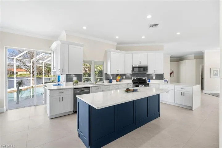 Sink with a view, kitchen with new modern shaker cabinetry, under cabinet lights, designer backsplash, a center island, quartz counters, and stainless steel appliances