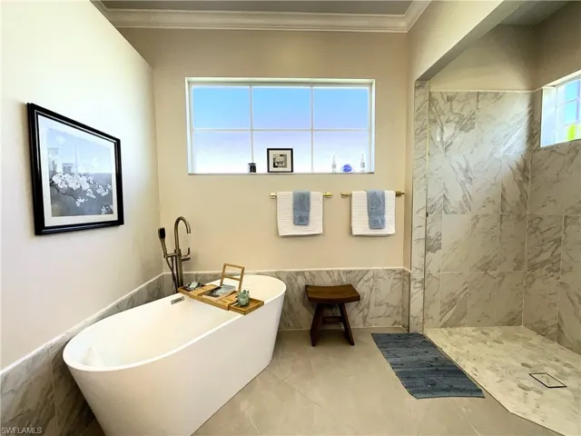 Bathroom featuring a freestanding bath, wainscoting, tile walls, and crown molding