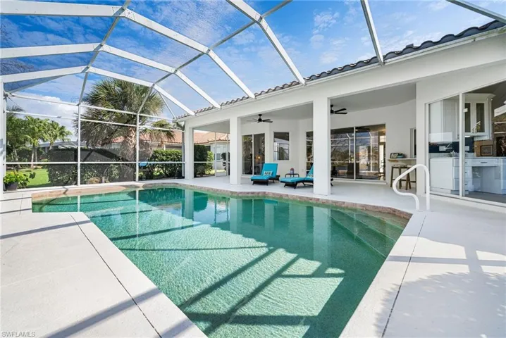 View of swimming pool featuring a lanai, an outdoor kitchen, ceiling fan, and a patio area