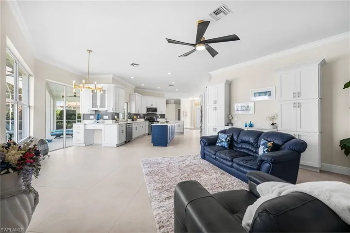 designer Tiled family/flex room featuring crown molding, extra pantry/cabinets built-in and ceiling fan with notable chandelier