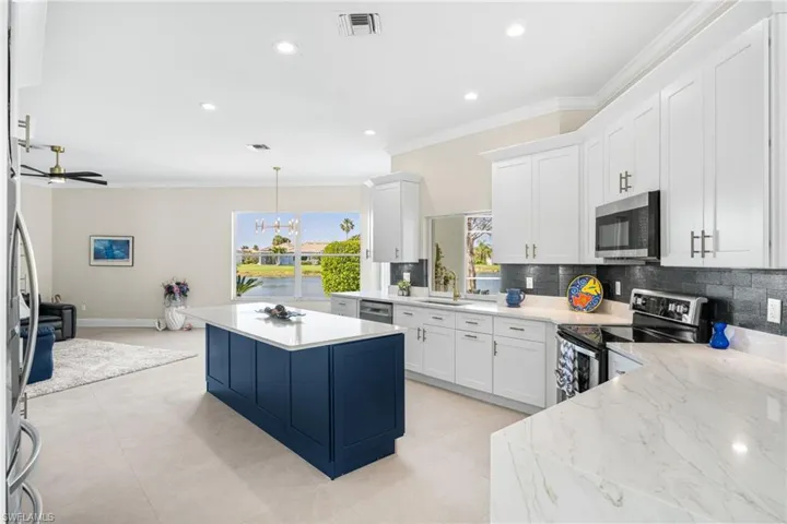 Kitchen featuring appliances with stainless steel finishes, tasteful backsplash, shaker cabinetry, large crown moldings, coffee bar and 32 inch designer tiles.