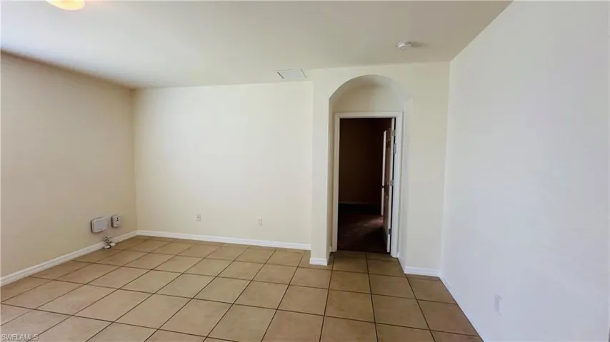 Spare room with arched walkways and light tile patterned floors