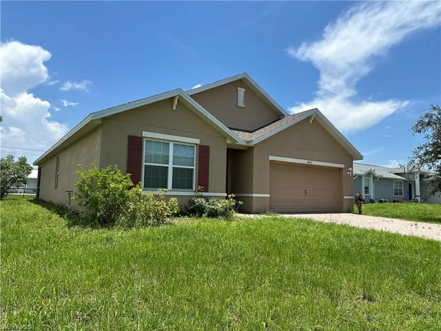 Ranch-style house featuring stucco siding, an attached garage, a front yard, and driveway
