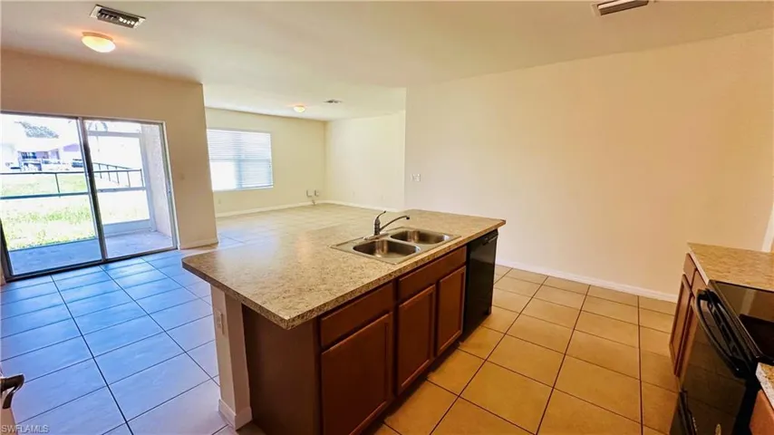 Kitchen featuring open floor plan, light tile patterned floors, black appliances, and light countertops