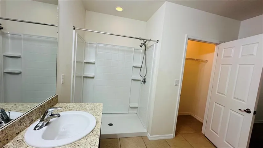 Full bath with a stall shower, tile patterned floors, vanity, and a spacious closet