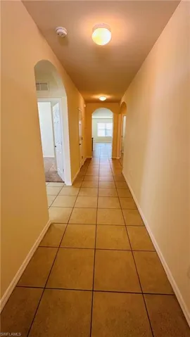 Corridor featuring light tile patterned floors and arched walkways