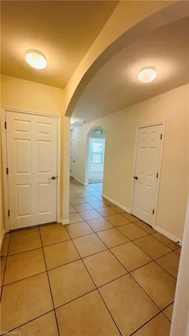 Hallway with light tile patterned flooring and arched walkways