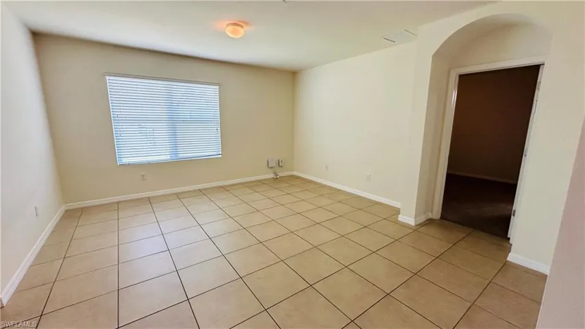 Empty room featuring arched walkways and light tile patterned floors