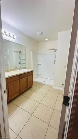 Bathroom featuring double vanity, tile patterned floors, and a shower stall
