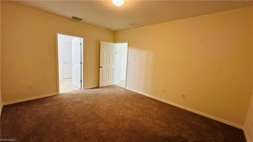 Spare room featuring light carpet and baseboards