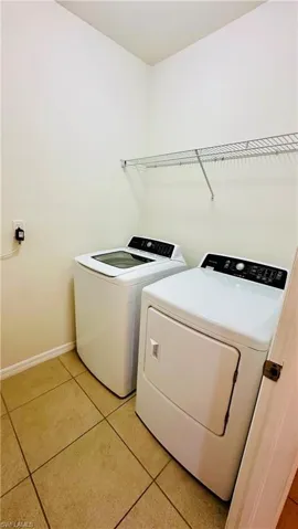 Laundry room with washer and dryer and light tile patterned flooring