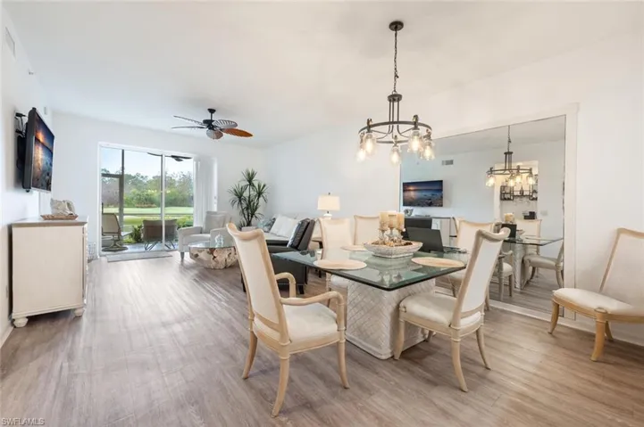 Dining area featuring ceiling fan with notable chandelier and wood-type flooring
