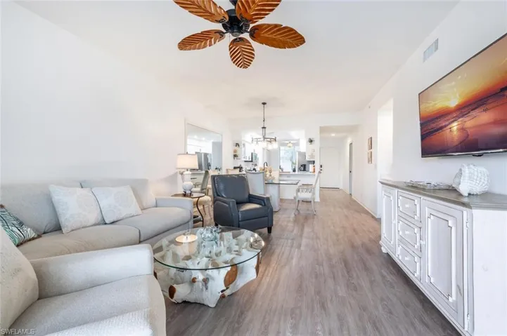 Living room with hardwood / wood-style flooring and ceiling fan with notable chandelier