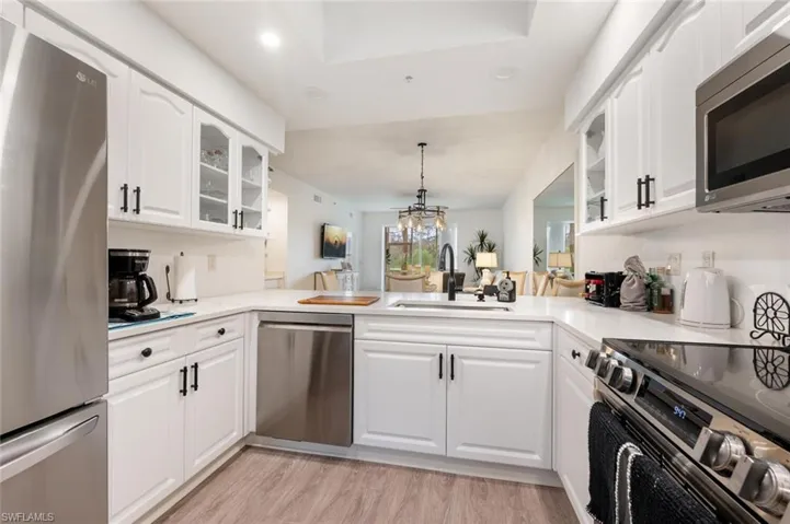 Kitchen featuring appliances with stainless steel finishes, kitchen peninsula, sink, and white cabinets