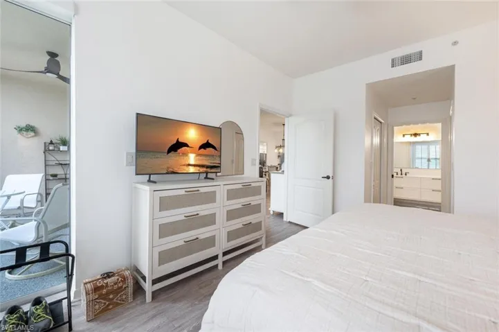 Bedroom with dark hardwood / wood-style floors and connected bathroom
