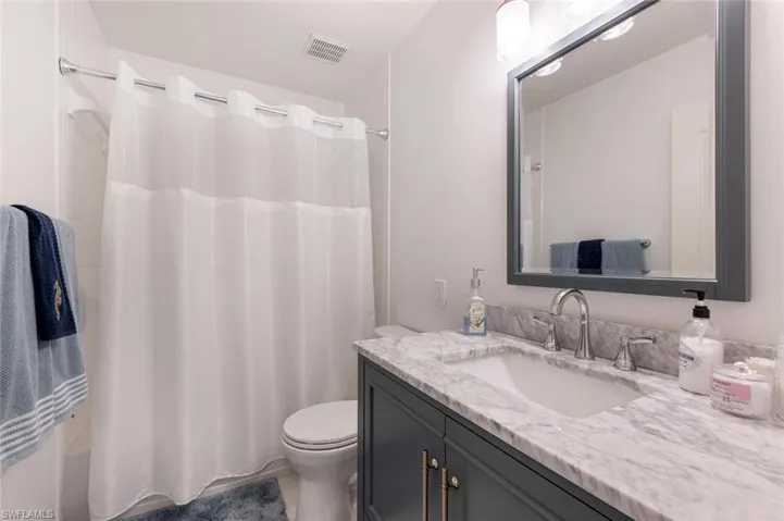 Bathroom with vanity, toilet, and a shower with shower curtain