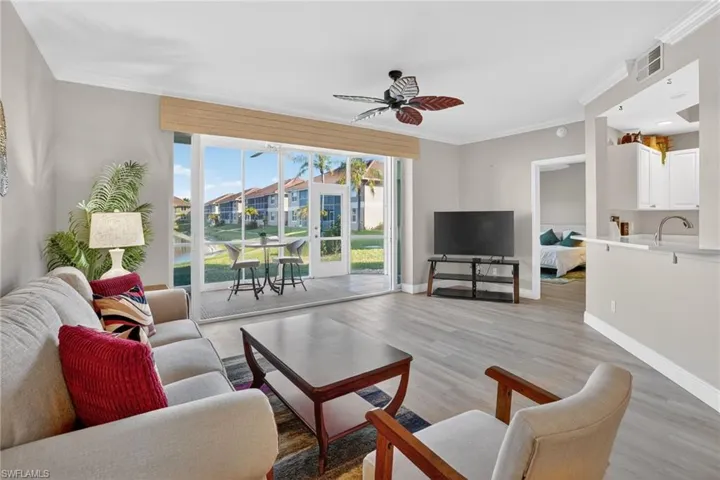 Living room with crown molding, wood finished floors, and ceiling fan