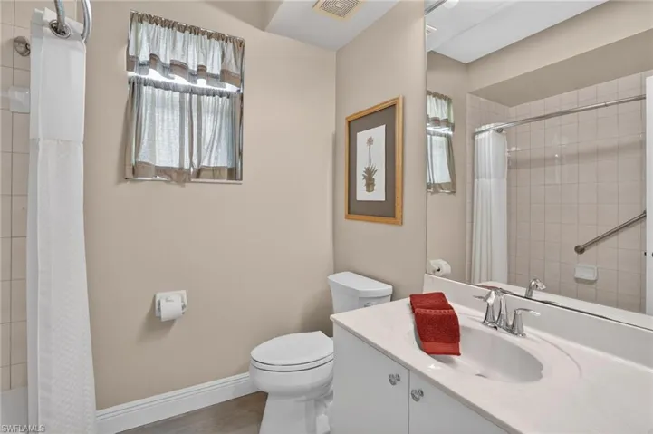 Bathroom featuring vanity, shower / bathtub combination with curtain, and wood finished floors