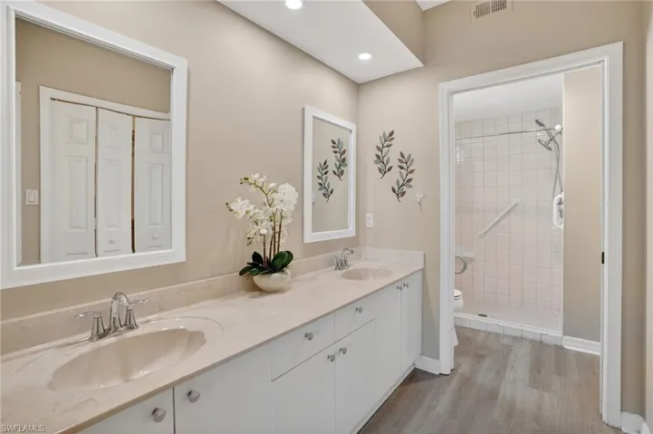 Bathroom with double vanity, a stall shower, light wood-style floors, and recessed lighting