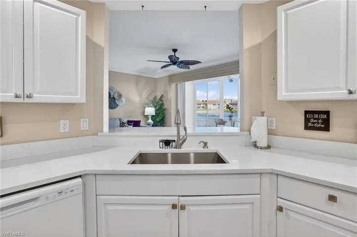 Kitchen featuring dishwasher, white cabinetry, light stone counters, and ceiling fan