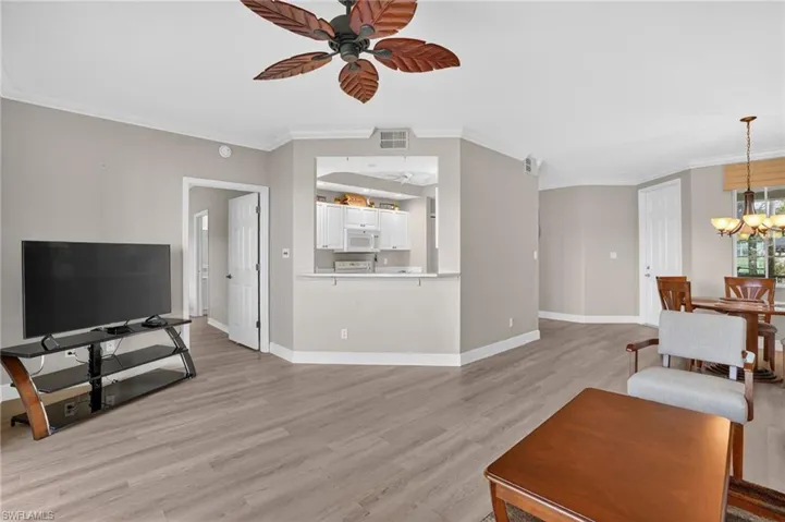 Living area with ornamental molding, light wood finished floors, ceiling fan, and a chandelier