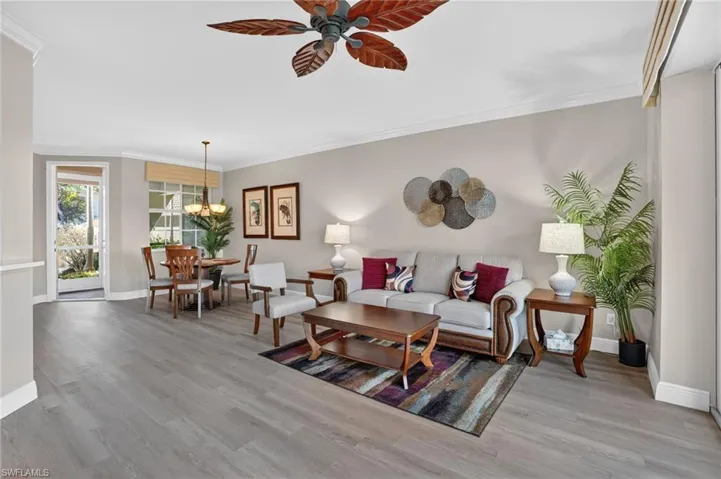 Living room with ornamental molding, a ceiling fan, light wood-type flooring, and a chandelier