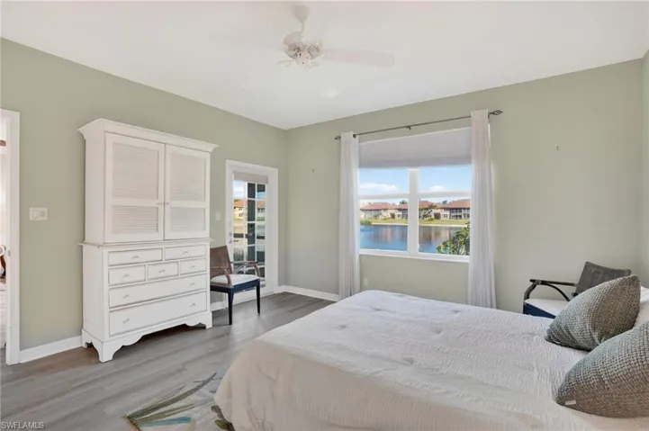 Bedroom featuring light wood-style floors, ceiling fan, a water view, and access to exterior
