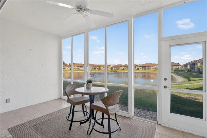 Sunroom with expansive windows, a textured wall, a residential view, a textured ceiling, and a water view