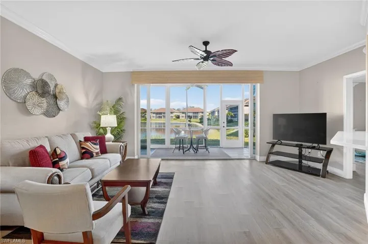 Living room with a ceiling fan, light wood finished floors, and crown molding